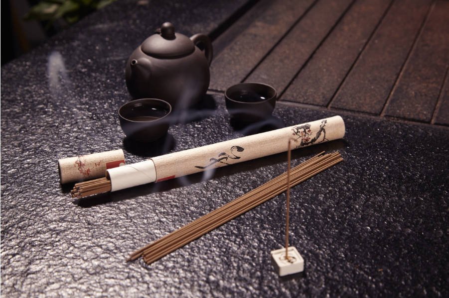 A single cultivated agarwood stick mid-burn, with a steady translucent smoke trail signaling a pure binder-light formulation